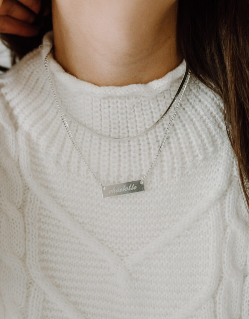 Image of model wearing layered set of Engraved Sterling Silver Name Bar Necklace and Sterling Silver Herringbone Chain Necklace