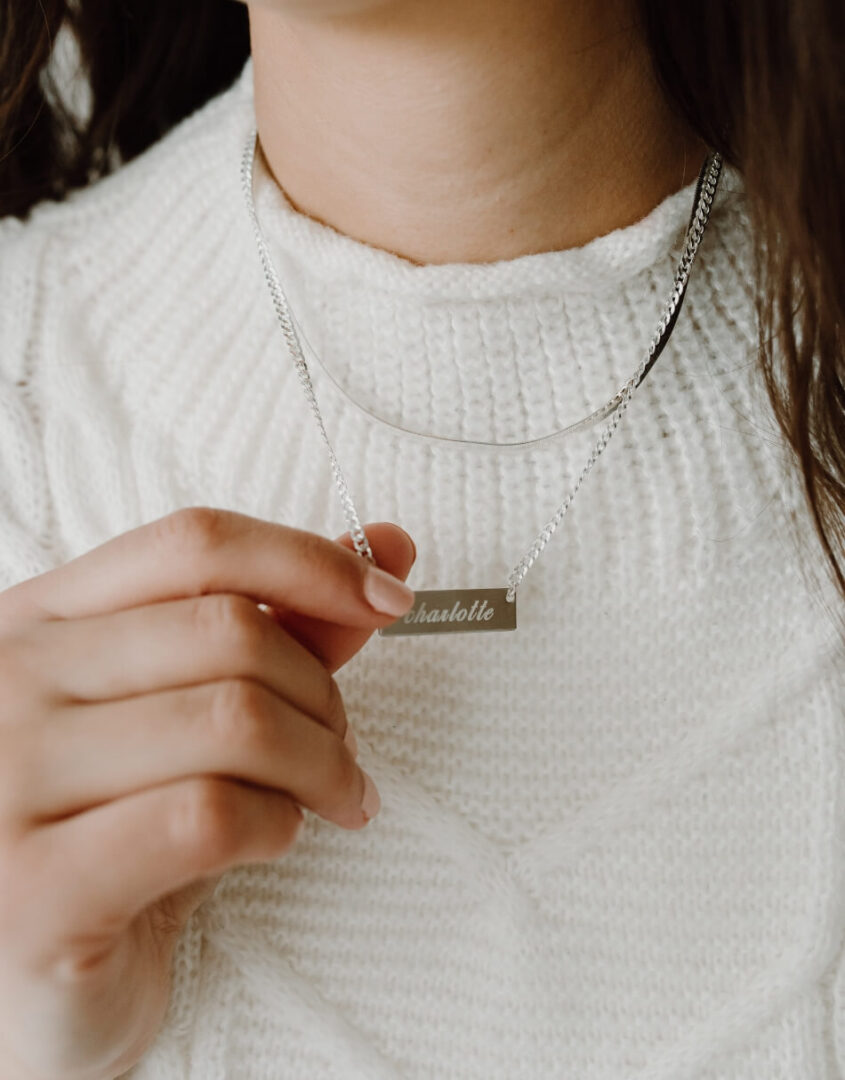 Image of model wearing layered set of Engraved Sterling Silver Name Bar Necklace and Sterling Silver Herringbone Chain Necklace