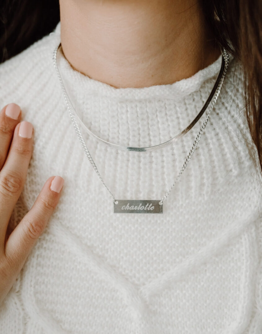 Image of model wearing layered set of Engraved Sterling Silver Name Bar Necklace and Sterling Silver Herringbone Chain Necklace