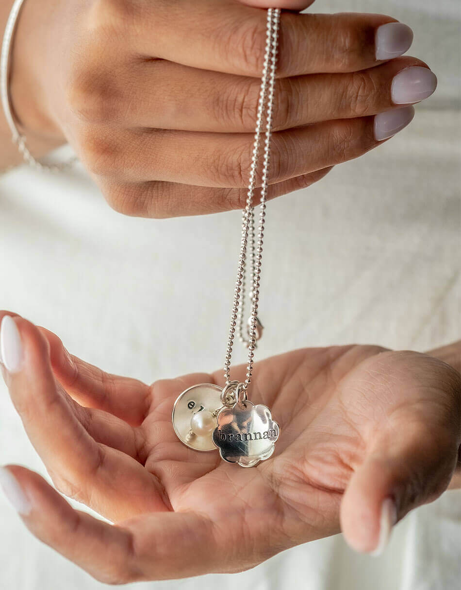 Best personalized necklace for a mom of 2. A flower and a circle charm with names hand stamped