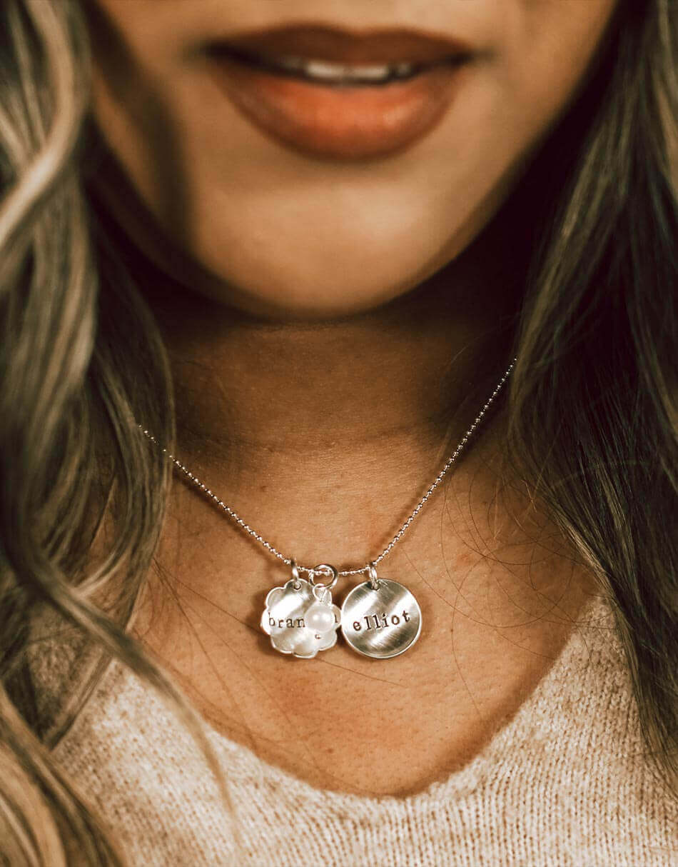 Name necklace with charms in the shape of flower and circle