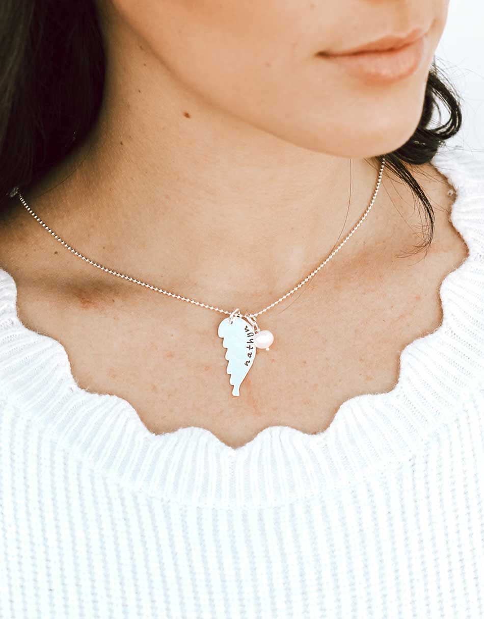 A sterling silver angel wing sentimental remembrance necklace, hand-stamped with any word or name.