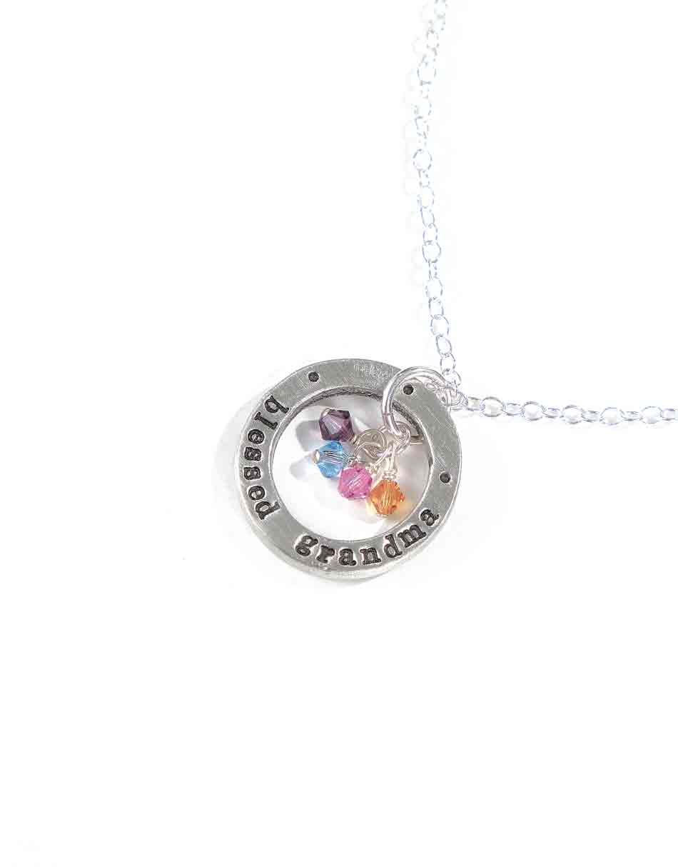 A sterling silver circle hand stamped with "blessed grandma" along with grand children birthstones. Perfect gift for a grandma