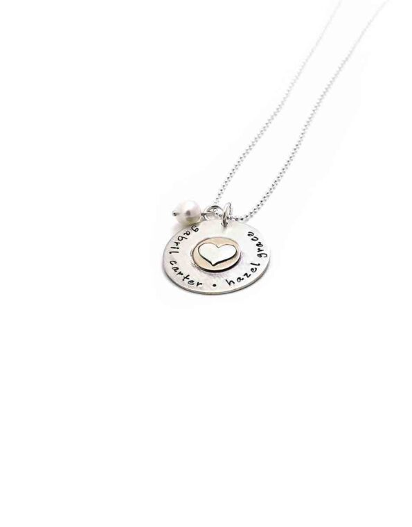 A sterling silver disc with hand stamped names. Layered with a gold-filled disc and a sterling silver heart in the middle.
