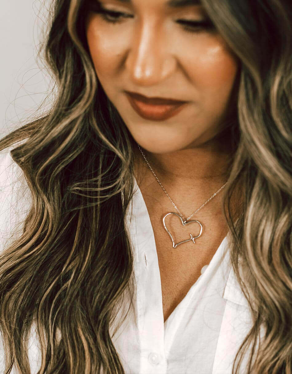 An imperfect heart hand forged in sterling silver and hung on a sterling silver chain. Perfect cross necklace for women