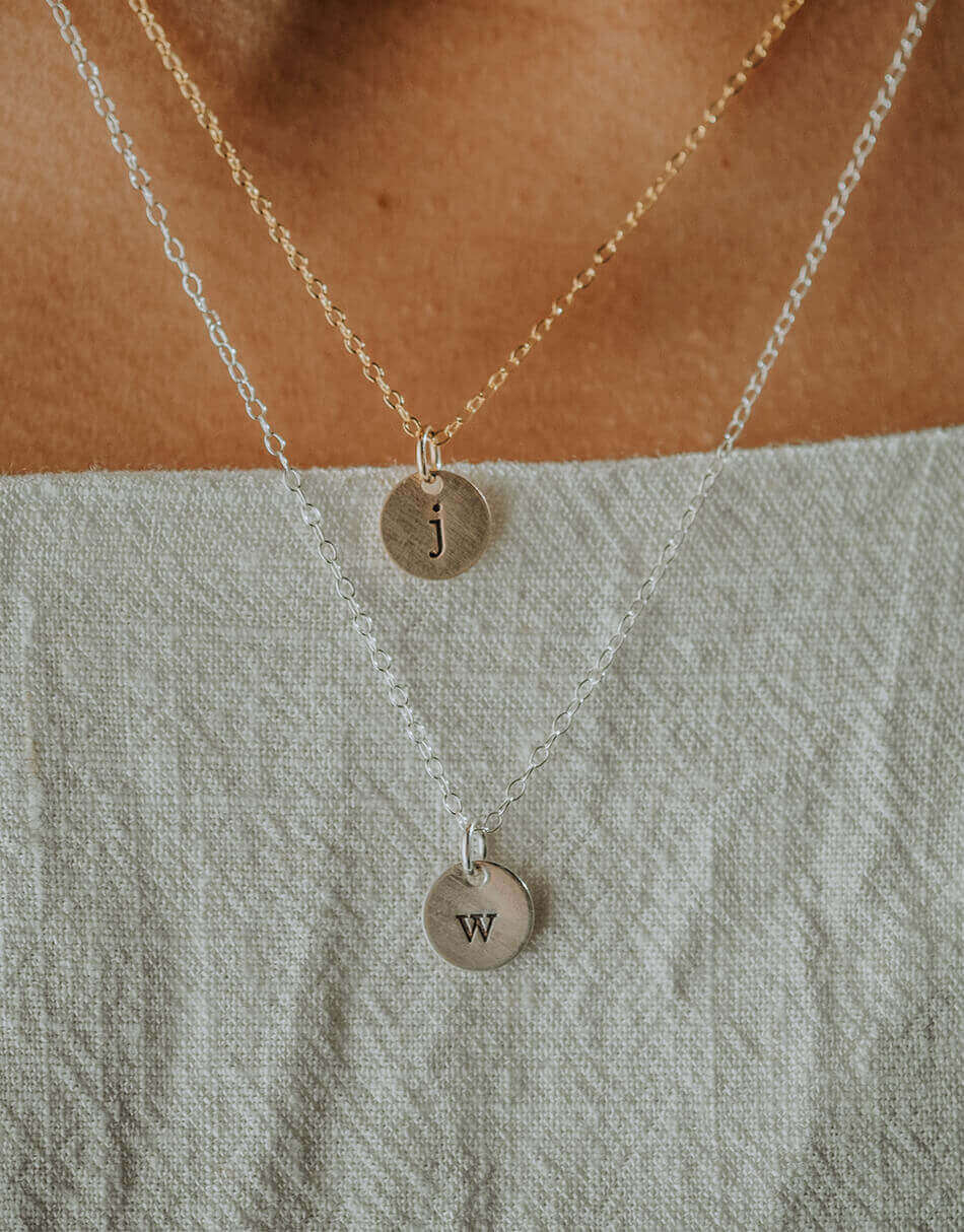 Hand-stamped initial on a tiny disc. Available in sterling silver or gold. Great personalized jewelry for wife, mom, new mom